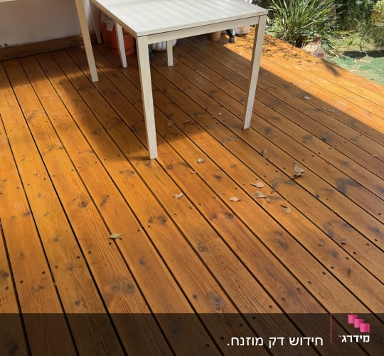 דק עץ עם שולחן לבן בגינה